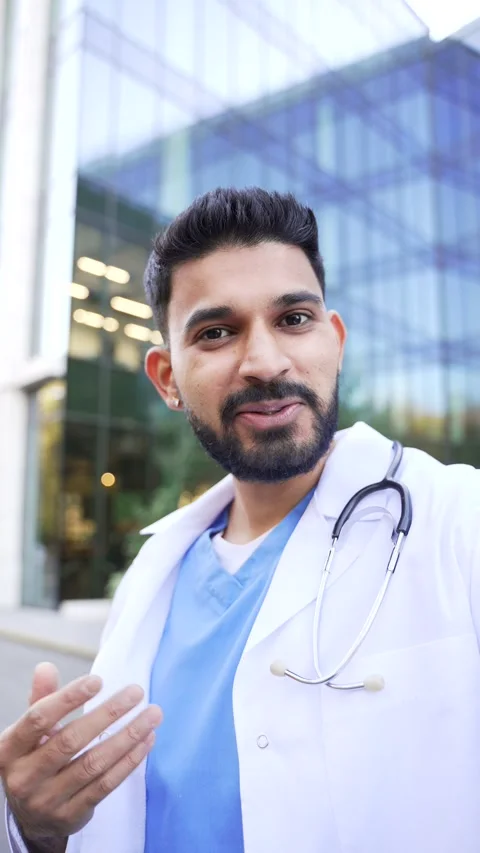 POV Vertical. Smiling doctor talking online via video call using a phone looking 스톡 동영상 344435265