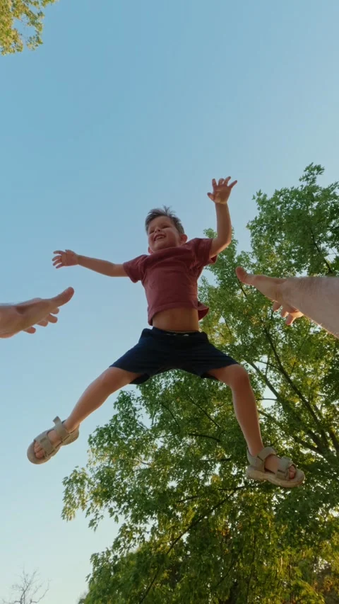 POV view, a father high throws and catches his laughing son in a park. Stock Footage 315979749