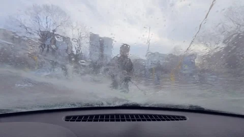 POV view from inside a car during manual car wash as a worker sprays water and f Stock-Footage 326293480