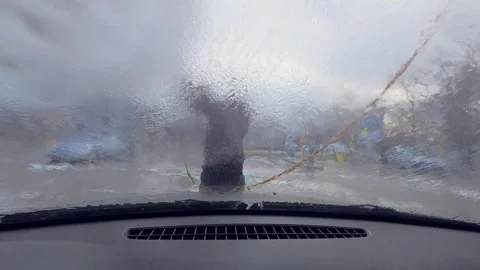 POV view from inside a car during manual car wash as a worker sprays water and f Stock Footage 326293526