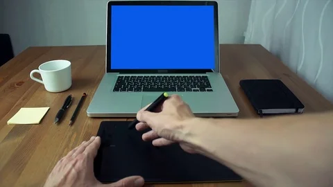POV view male hands using graphic tab and laptop with green screen at white desk Stock Footage 83253933