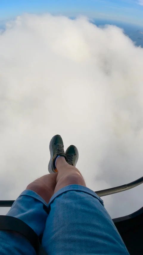 POV view of a man's legs and feet dangling over a thick layer of clouds during Stock-Footage 345734691