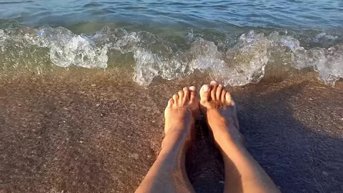 POV view of two female legs relaxing on beach on sunny day. 스톡 동영상 270252753