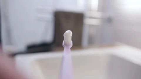 POV view of unrecognizable girl hand squeezing white toothpaste onto purple Stock Footage 249283553