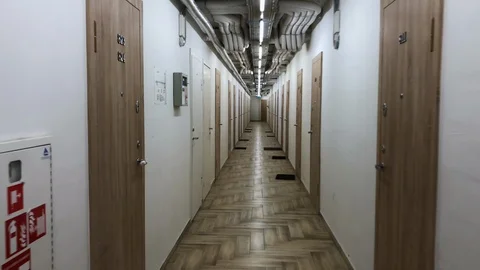 POV view: Walking through empty long corridor with many doors on the side 動画素材 121536296