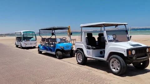 POV walking past electric shuttle carts on beach promenade in Sahl Hasheesh. Stock Footage 337533494