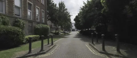 Pov of walking a road next to a red brick building - HLG Footage Video stock 196113908