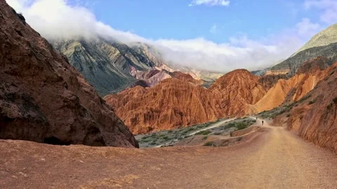 POV Walking Through Metallic-Toned Mountains with Distant Figures Stock Footage 296074699