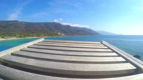 Pov of a wooden beach chair by the sea in Sardinia, Italy Stock Footage