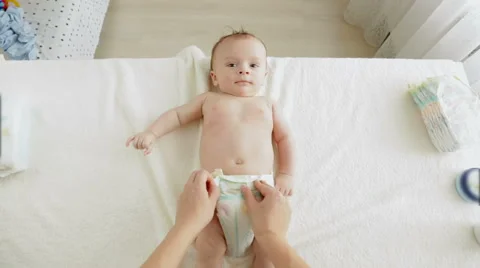 POV young mother taking dirty diapers of adorable baby boy lying on table Stock Footage
