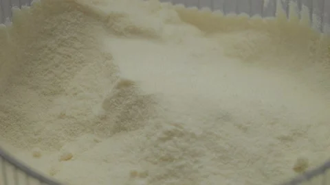 Powdered milk falls gracefully into a container in close-up view Stock Footage 327582378