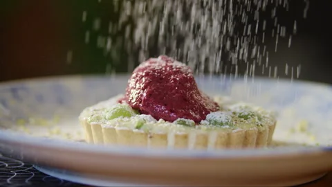 Powdered sugar being poured into grape tart on plate Stock Footage 274714618