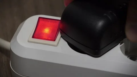 Power adapter is inserted into the electric portable socket with red indicator Stock Footage 323867348
