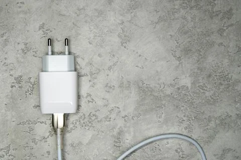 Power adapter with USB cable on gray. Charger for home electronics Stock-Fotos