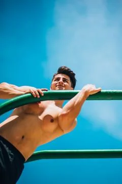 Power athletic guy execute exercise on parallel bars Stock Photos