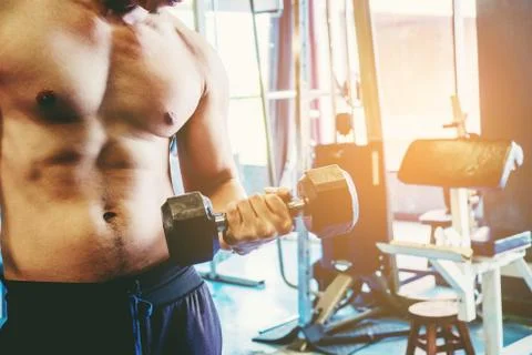 Power athletic Man bodybuilder exercise with dumbbells in gym Stock Photos