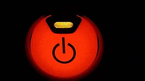 Power button on device with bright color in dark background at night Stock Photos