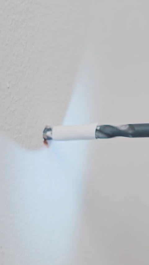 Power drill boring a hole into a white wall close up Stock Footage 345659618