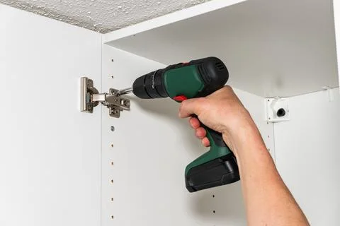 Power drill installing hinge inside cabinet Fotos Stock