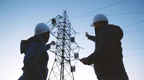 Power engineers in protective helmets are building a power line, working with a Fotos de archivo