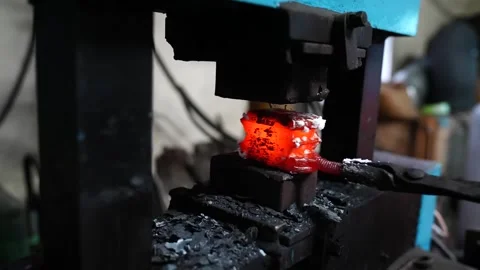 Power hammer compressing a white hot layered billet as scale and sparks fall Stock Footage 343370816