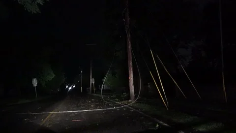 Power line down laying in road way as car approaches Stock Footage 252136467