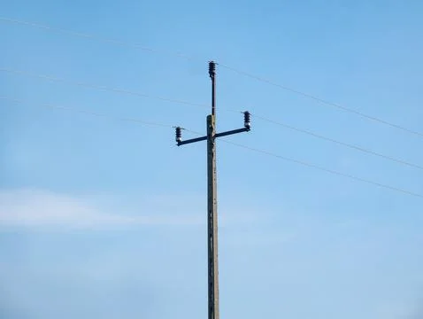 Power line going through dirt road under cloudy sky Foto stock