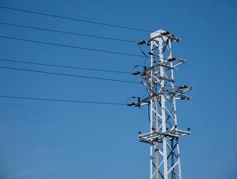 Power line going through dirt road under cloudy sky Foto stock