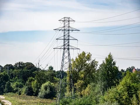 Power line going through dirt road under cloudy sky Foto stock