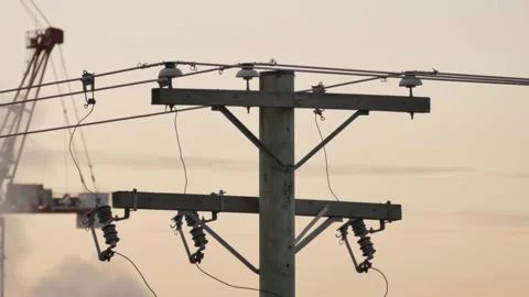 Power line with insulators at sunset crane faintly visible in the background Stock Footage 319179545
