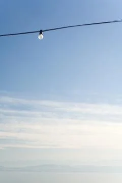 Power line with a single light bulb, cloudy sky, low angle view Stock Photos