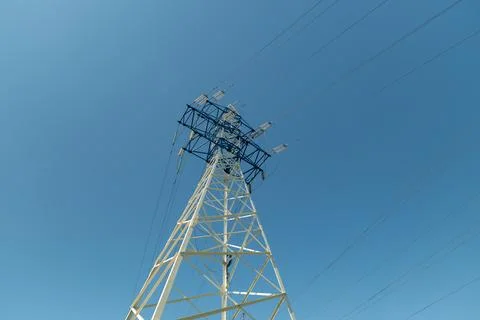 Power line structure stands tall against a clear blue sky in a rural area d.. Stock Photos