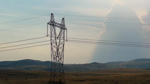 Power line tower against sunset sky in hilly landscape. A scenic view of a po Stock Footage 296357238