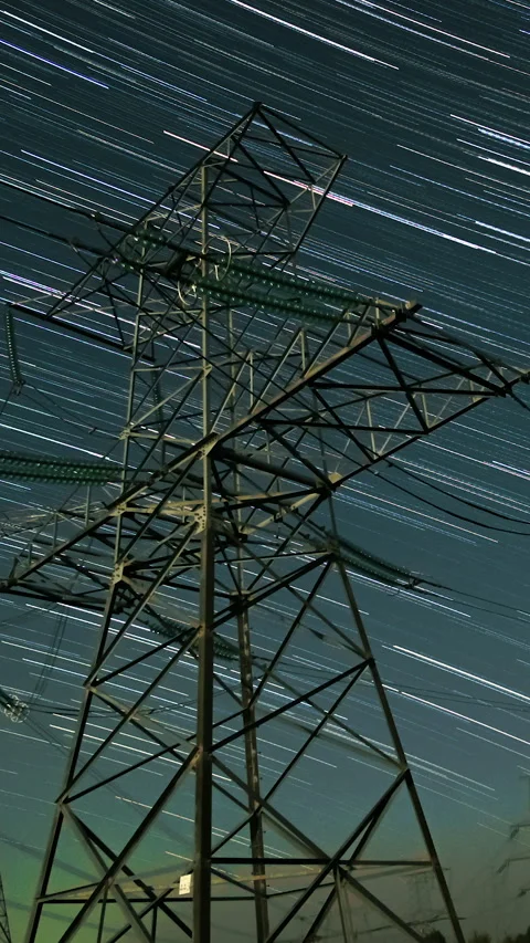 Power line tower under star trails in night sky long exposure scene Stock Footage 336435811