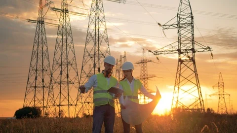 Power line workers working with a construction plan on a sunset background. Video stock 94840132