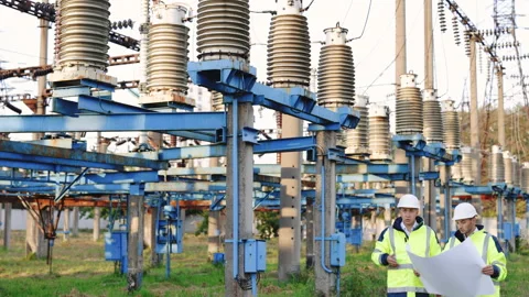 Power line workers working with a construction plan on a sunset background. Two Stock-Footage 194620516