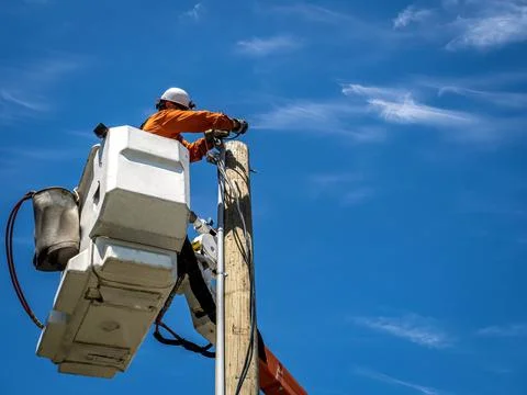 Power lineman at work in an aerial bucket connecting a new house service on a Stock Photos