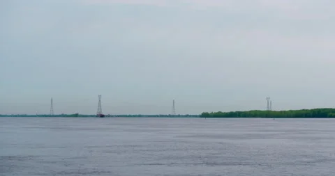 Power lines and cargo ship with cloudy sky at the river Stock Footage 130989295