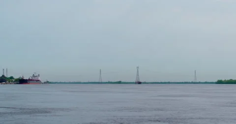 Power lines and cargo ship with cloudy sky at the river Stock Footage 130989493