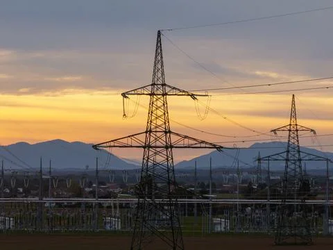 Power lines and transmission towers against a sunset sky in an aerial view Stock Photos