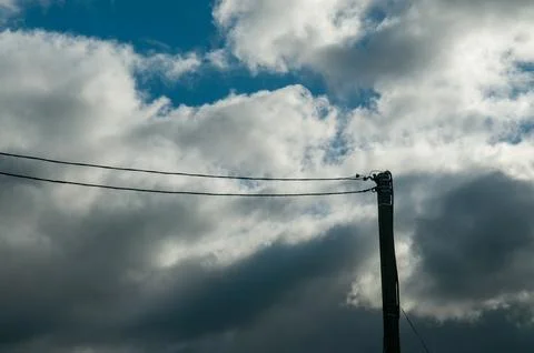 Power lines and utility pole against a cloudy sky Stock Photos