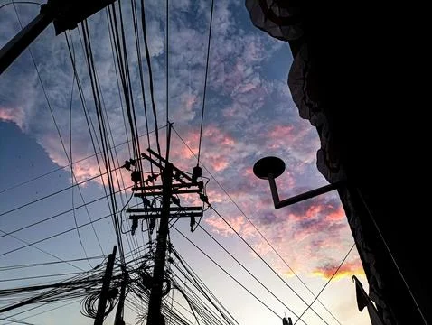 Power lines and utility pole against a colorful sunset sky. Silhouette of w.. Stock Photos