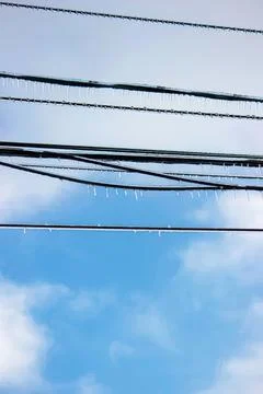 Power lines on a bright blue sky with clouds Stock Photos