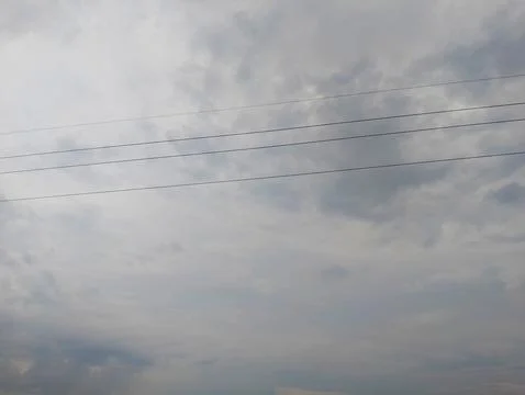 Power lines cut through a cloudy sky hinting at an upcoming storm Stock Photos