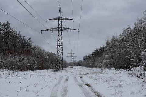 Power lines cutting through snowy landscape on cloudy day Stock Photos
