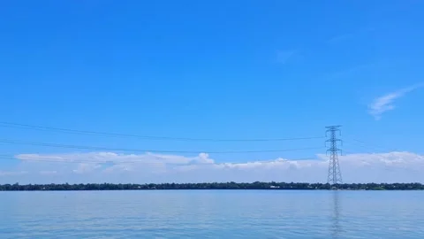 Power lines over a calm lake with a blue sky Vídeo Stock 331806823