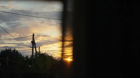 Power lines silhouetted against a dramatic sunset sky Stock Photos