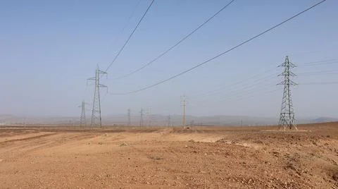 Power lines stretch across a dry, golden field Stock Photos