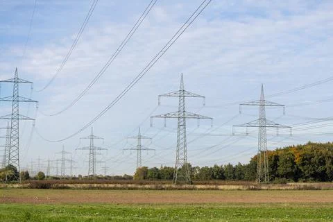 Power lines stretch across fields under a cloudy sky in a rural landscape during Stock Photos