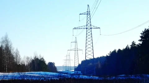 Power lines stretch across a snowy landscape with trees in the background during Stock Footage 328116953